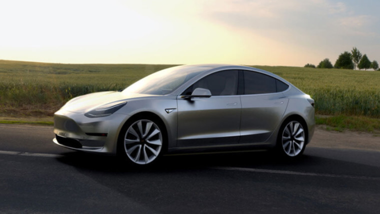 A Tesla Model 3 on the road in the sunlight