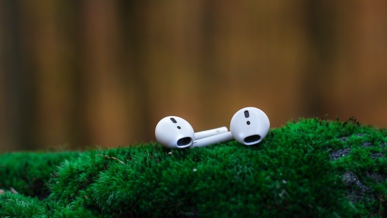 Apple AirPods on a green surface