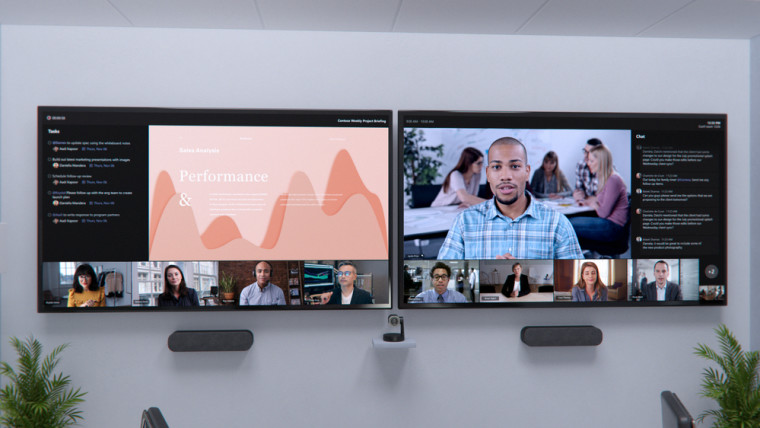 Two large screens running a Teams meeting with multiple video feeds shown across both of them