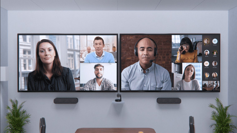 Two large screens running a Teams meeting with multiple video feeds shown across both of them
